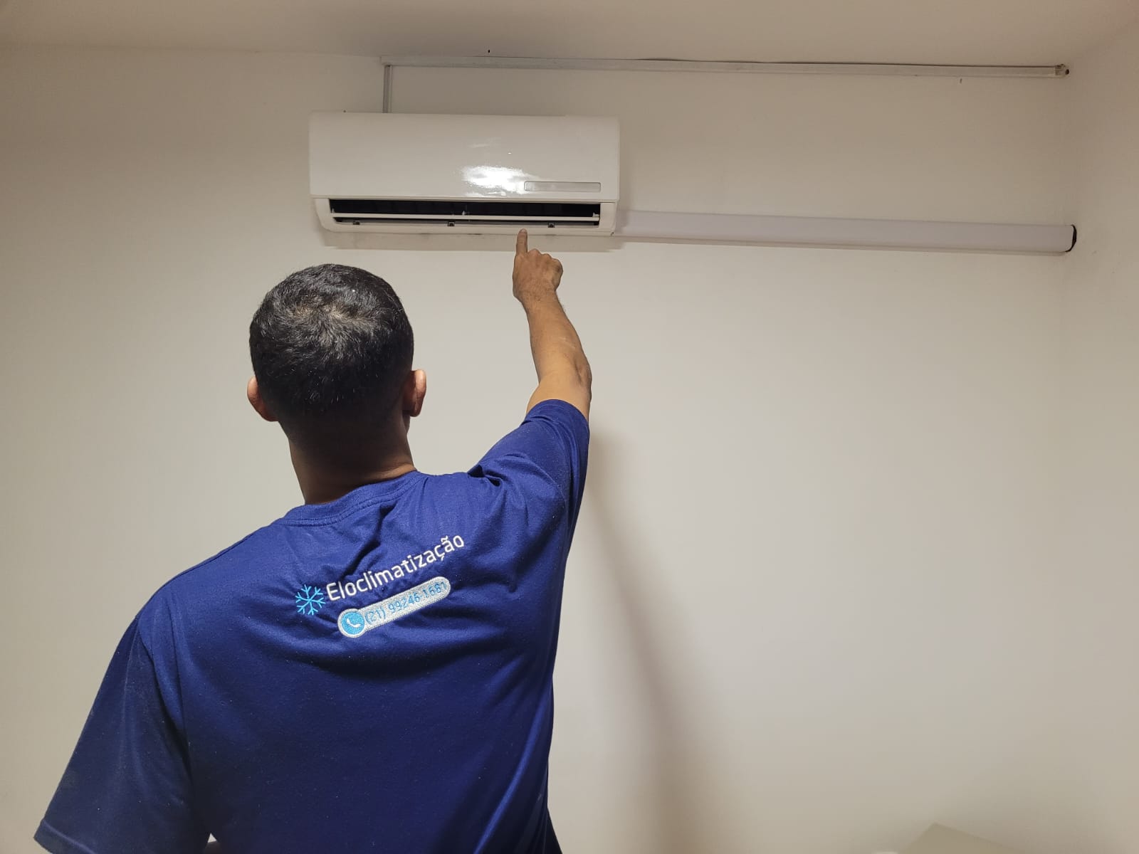 Técnico da EloarTech com uniforme conferindo instalação de ar-condicionado